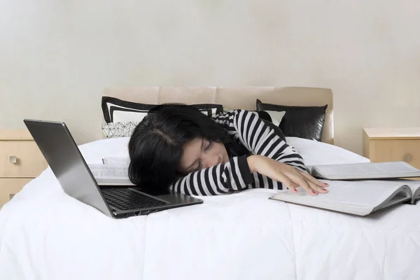 Chica duerme en la cama con el ordenador portátil y libros de texto —  Fotos de Stock