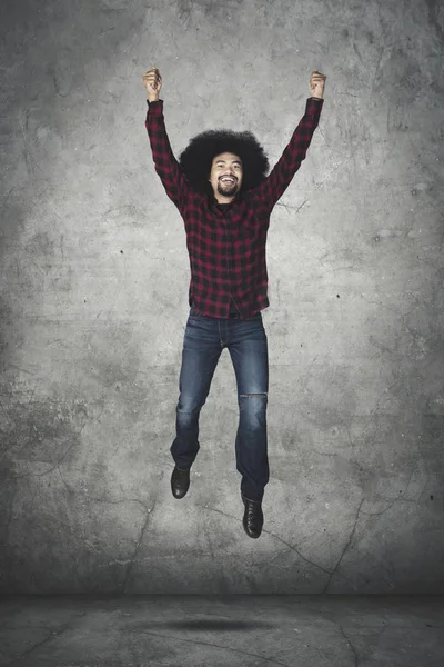 Alegre hombre afro salta mientras levanta las manos — Foto de Stock