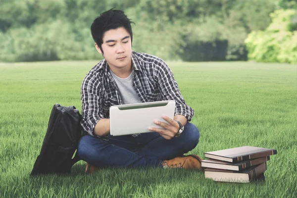 Male college student with tablet in the meadow — Stock Photo, Image