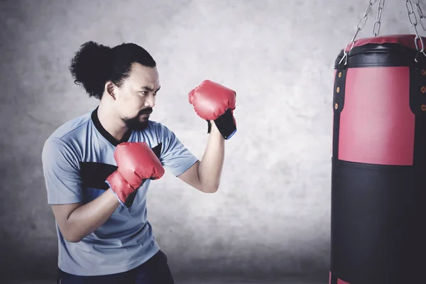 Hombre practica boxeo con saco — Foto de Stock