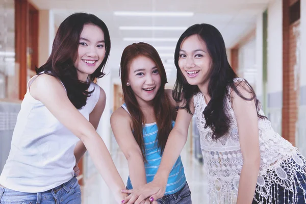 Pretty female students joining hands together — Stock Photo, Image