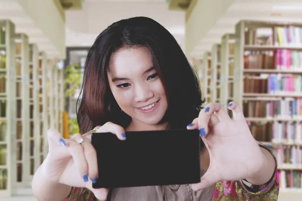 Estudante bonita fazendo selfie na biblioteca — Fotografia de Stock