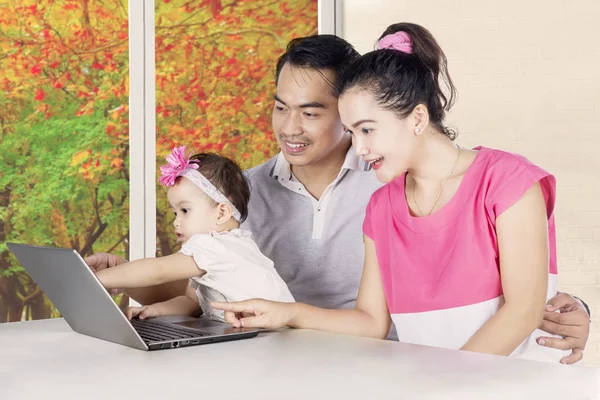 Sorrindo pais e criança olhando para laptop — Fotografia de Stock