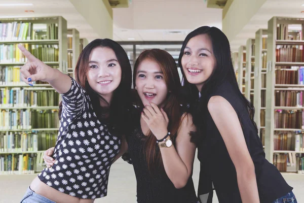 Tre kvinnliga studenter tittar på något — Stockfoto