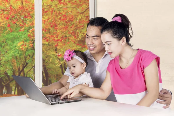 Молодые родители и девочка смотрят на ноутбук — стоковое фото