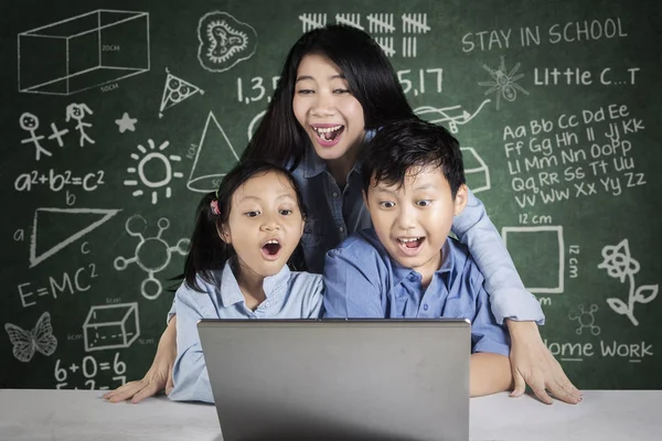 Νεαρή δασκάλα και τους μαθητές που φαίνονται στο φορητό υπολογιστή — Φωτογραφία Αρχείου