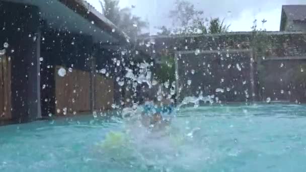 Zeitlupe eines Jungen, der Wasser ins Wasser spritzt — Stockvideo