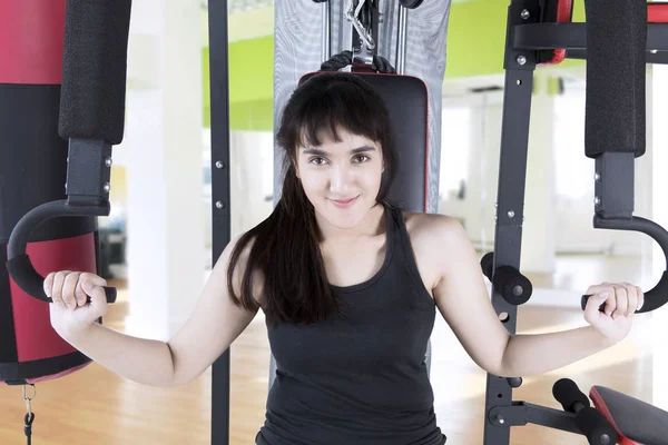 Hermosa mujer sentada en el equipo de gimnasio — Foto de Stock