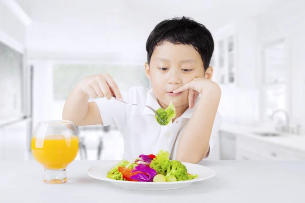 Criança salada de degustação na cozinha — Fotografia de Stock