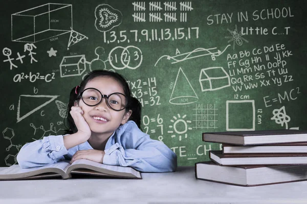 Söt skolflicka med läroböcker i klassrummet — Stockfoto