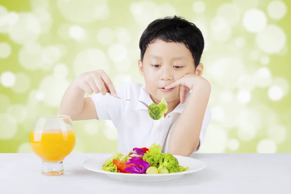 Missnöjd pojke äter sallad — Stockfoto