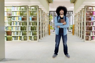 Kütüphanede duran erkek Afro öğrenci
