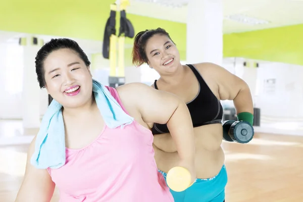 Las mujeres gordas levantan pesas en el gimnasio — Foto de Stock