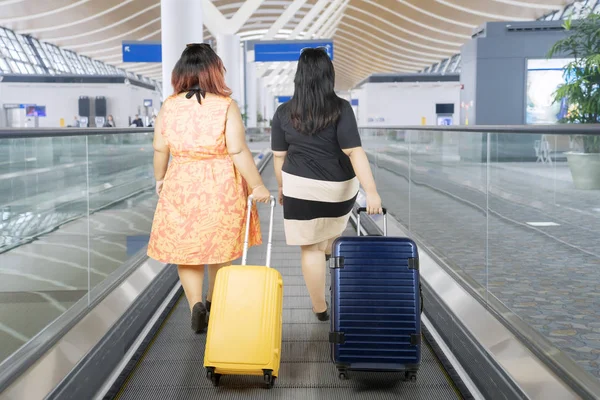Tlusté ženy chodit na letišti po eskalátoru — Stock fotografie