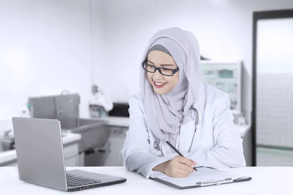 Female doctor working with a laptop and clipboard — Stock Photo, Image