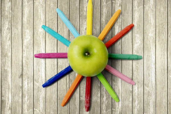 Grüner Apfel mit Buntstiften auf dem Tisch — Stockfoto