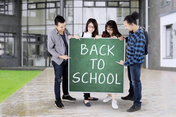 Los estudiantes felices retienen el texto de Back to School —  Fotos de Stock
