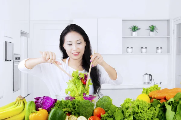 Υγιή γυναίκα ανακατεύοντας σαλάτα στην κουζίνα — Φωτογραφία Αρχείου