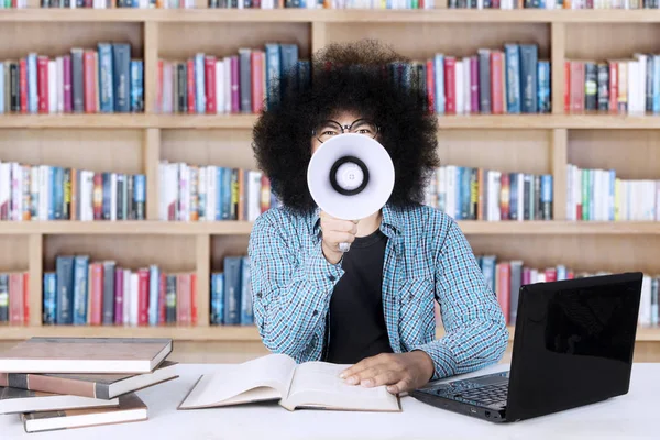 Male student with a megaphone in the library — Stock Photo, Image