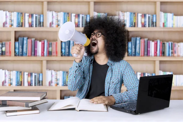 Studente maschio con megafono in biblioteca — Foto Stock