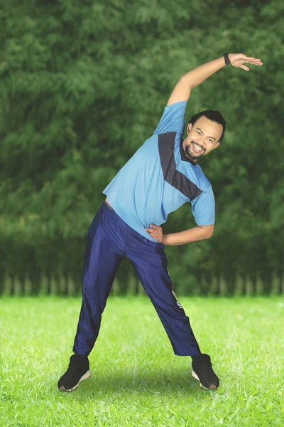 Uomo che fa stretching posizione nel parco — Foto Stock