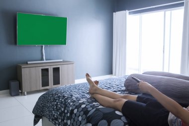 Genç kadın yatak odasında televizyon izleyen