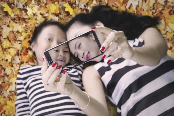 Mamma e figlia scattare selfie con foglie autunno — Foto Stock