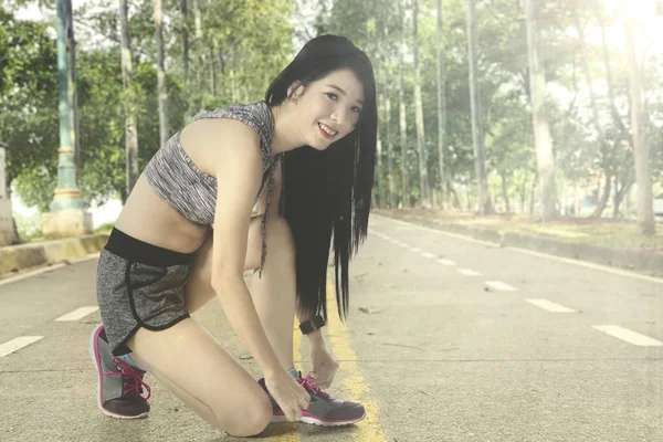 Slim donna allacciatura lacci delle scarpe al parco — Foto Stock