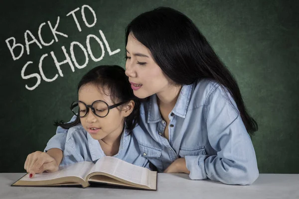 Lärare undervisar en flicka att läsa — Stockfoto