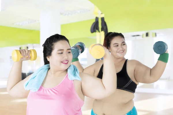 Dos mujeres con sobrepeso levantando pesas — Foto de Stock