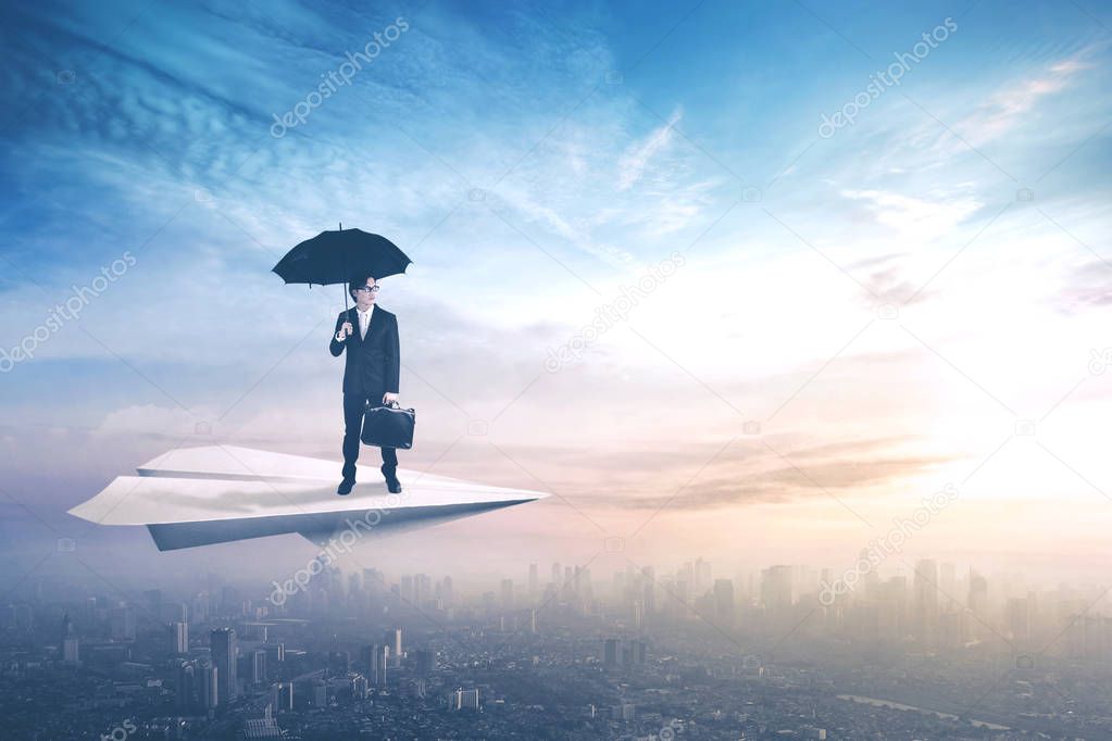 Worker with umbrella on paper aircraft
