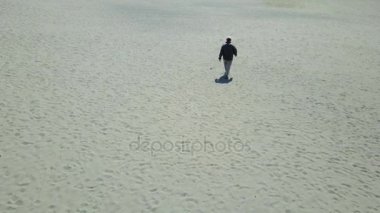 Sahil kumu üzerinde yürüyen bir adam havadan görünümü