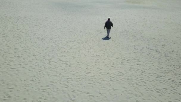 Vista aérea de um homem caminhando na areia da praia — Vídeo de Stock