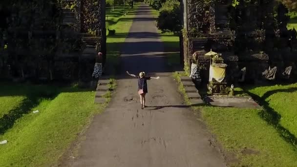 Mujer feliz entrando a la puerta tradicional balinesa — Vídeo de stock