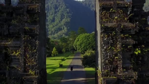 Mulher que entra no parque com portão tradicional balinês — Vídeo de Stock