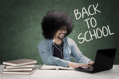 Bir laptop ve kulaklık kullanarak Afro öğrenci