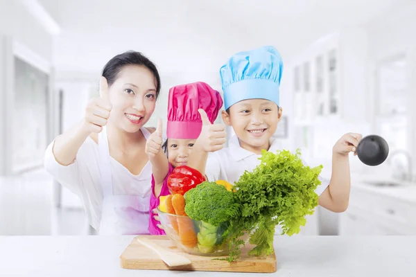 Asiatisk familj med tummen upp och grönsaker — Stockfoto