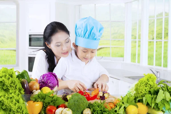 Menino e mãe corte de legumes — Fotografia de Stock