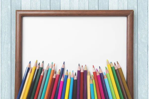 Pensil berwarna dengan bingkai kosong di atas meja — Stok Foto
