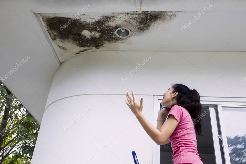 Depressed woman with damaged ceiling