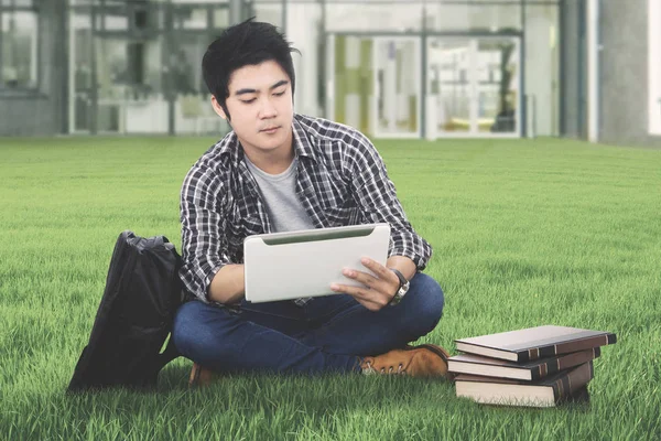 Male student with tablet in the campus yard