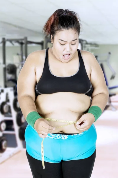 Избыточный вес женщины измеряет ее живот — стоковое фото