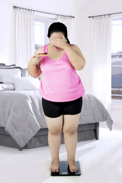 Избыточный вес женщины с весами в спальне — стоковое фото