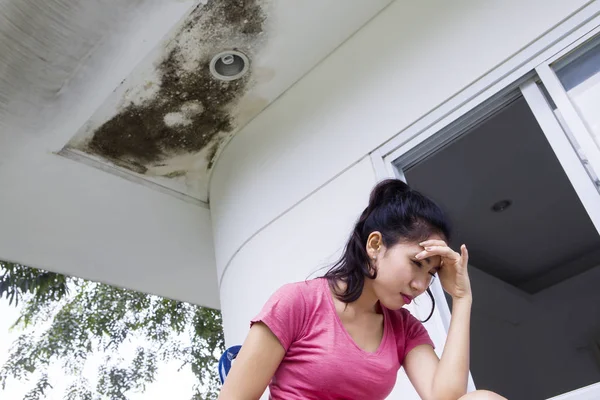 Mulher estressante sob teto danificado — Fotografia de Stock