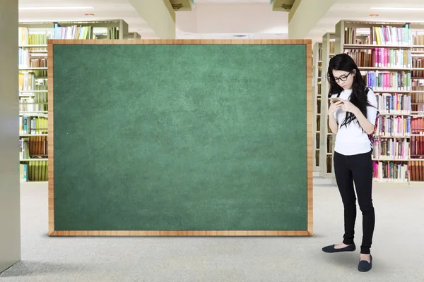 Student with blank blackboard in library — Stock Photo, Image