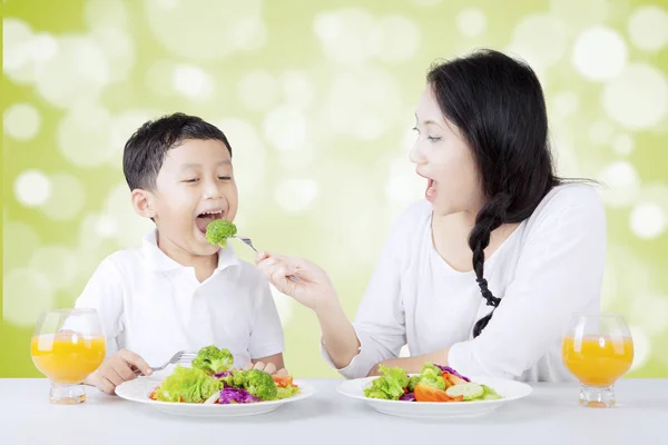 Mother feeding her son with fresh salad Stock Photo