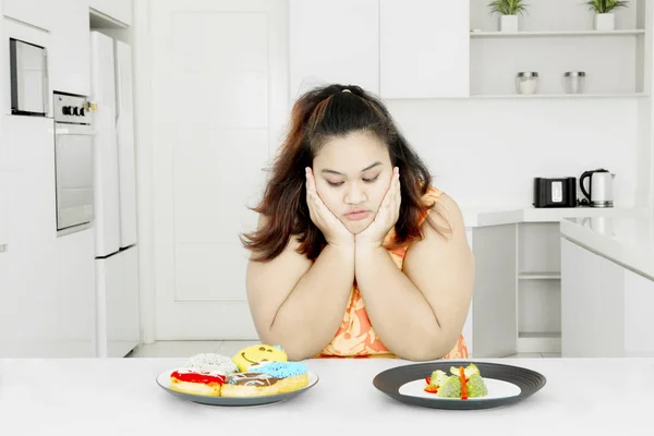 Mulher gorda com salada de legumes e donuts — Fotografia de Stock
