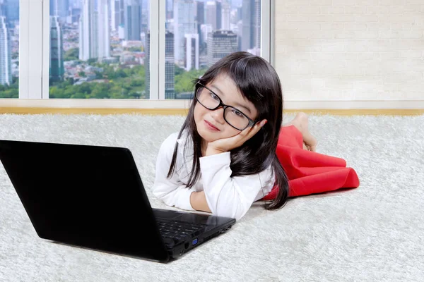 Liten flicka med laptop på mattan — Stockfoto