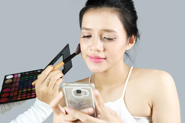 Красива жінка зі смартфоном робить макіяж — стокове фото