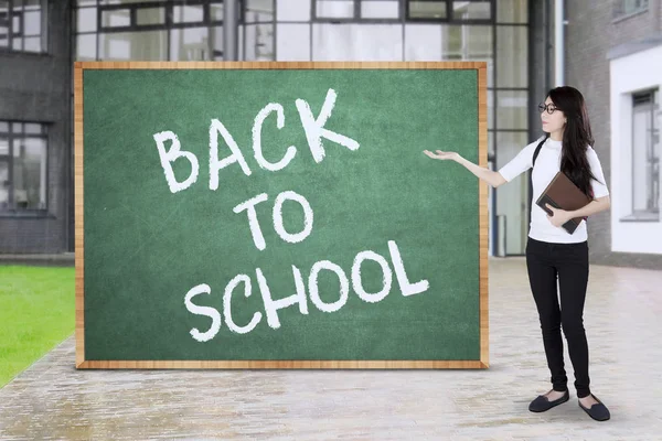 Student shows blackboard in school yard — Stock Photo, Image